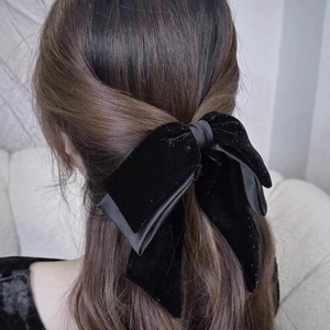 Detailed close-up of velvet bow hair clip with shimmering glitter on a half-up hairstyle