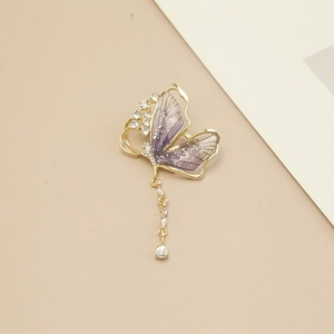 Élégante broche papillon dorée avec ailes violettes, glands en strass et gemme en forme de goutte