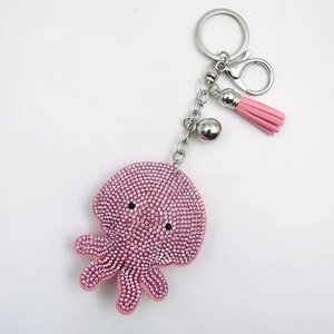 Pink rhinestone octopus keychain with leather tassel and silver bell on white background