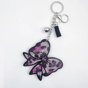 Vue détaillée du porte-clés nœud en cristal étincelant avec pompon en cuir et clochette