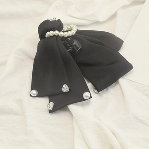 Detail of elegant black satin bow hair claw clip with faux pearls and heart rhinestones