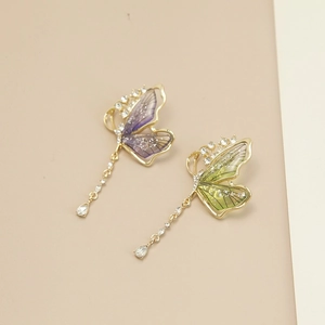 Détail de la boucle d'oreille papillon avec ailes en résine et pompon cristal