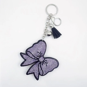 Détail du porte-clés nœud en cristal étincelant avec pompon en cuir noir et violet