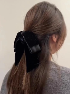 Detail of elegant black velvet hair claw clip with subtle glitter on a female model