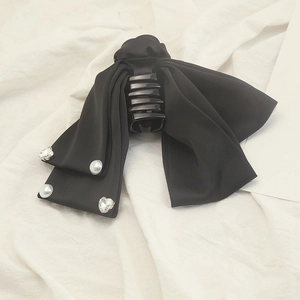 Detailed view of satin bow hair claw with elegant pearl and heart rhinestone accents