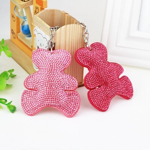 Detail of pink and fuchsia rhinestone bear keychains with tassels on a desk setup