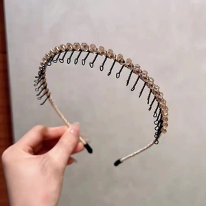 Détail des perles de cristal champagne et des dents de peigne sur un serre-tête noir