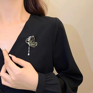 Détail du broche papillon émeraude avec des ailes en zircone dorée et pampille en goutte