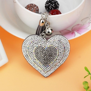 Detail of heart rhinestone keychain with grey leather tassel on a ceramic cup