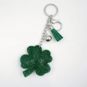 Detail of green crystal four-leaf clover keychain with matching tassel and bell charm