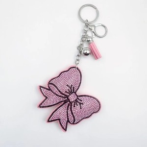 Détail du porte-clés nœud en cristal rose avec strass brillants et gland en cuir élégant
