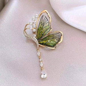 Détail de la broche papillon émeraude avec ailes vertes et glands en zircon brillant