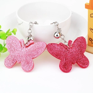 Detailed close-up of sparkling rhinestone butterfly keychains with silver bell charms