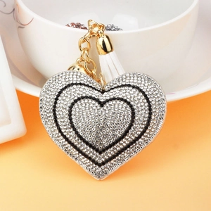 Sparkling heart keychain with rhinestones and white tassel on a bright surface