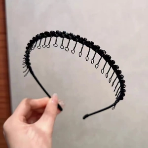 Détail d'un serre-tête à perles noires avec franges en chaîne métallique et résine