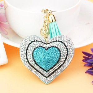 Macro detail of heart-shaped rhinestone keychain with blue tassels and golden bell