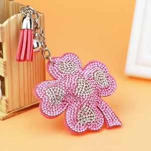 Detailed view of pink rhinestone clover keychain with tassel and bell accessory