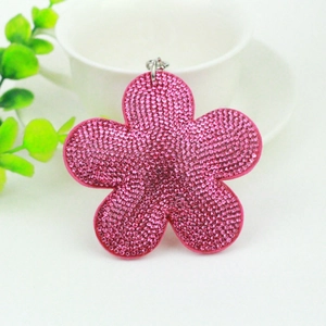 Pink rhinestone plum flower keychain with tassel detail on a white ceramic cup