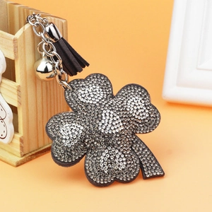 Close-up of sparkling rhinestone clover keychain with silver bell and black tassel detail