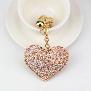 Sparkly pink heart keychain with crystals and gold lobster clasp on white saucer