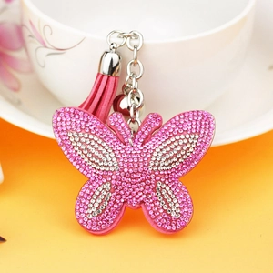Roze strass vlinder sleutelhanger met suède kwastje en zilveren bel op gele ondergrond