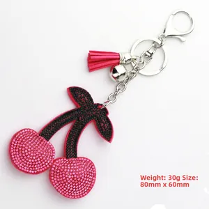 Detail of pink cherry rhinestone keychain with silver bell and stylish pink silk tassel