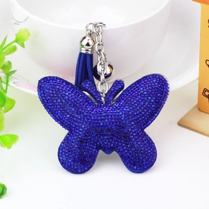 Velvet butterfly keychain with blue rhinestones and tassel hanging on a white table