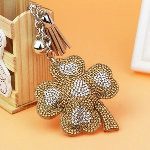 Sparkling four-leaf clover keychain with rhinestones, silver bell and brown tassel charm