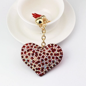 Sparkling heart rhinestone keychain with red tassel and gold metal chain on white cup