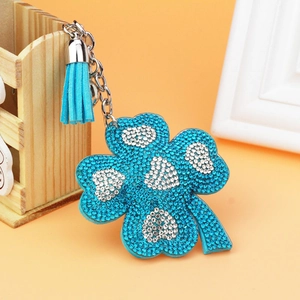 Detail of four-leaf clover keychain with sparkling blue rhinestones and leather tassel