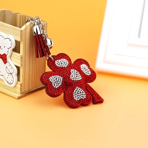 Detail of red clover keychain featuring sparkling rhinestones and a silk tassel