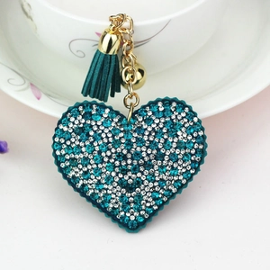 Detail view of heart keychain with blue and white rhinestones, green tassel and gold bell