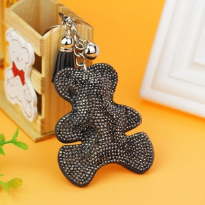 Close-up of leather bear keychain with black rhinestones, silver bells, and tassel