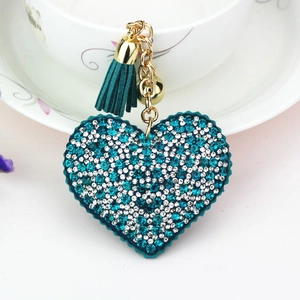 Detail view of heart-shaped rhinestone keychain with green tassel and gold accents