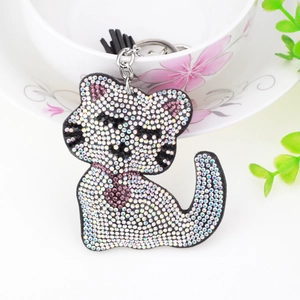 Détail d'un porte-clés chat en cristal avec strass blancs et pompon sur une tasse
