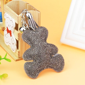 Detailed view of gray rhinestone bear keychain with leather tassel and silver bell ornament