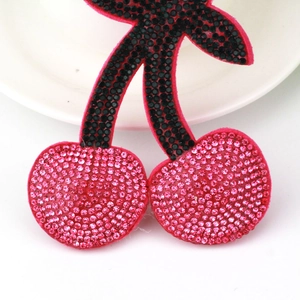 Sparkling cherry keychain with pink rhinestones and black tassel on a white plate