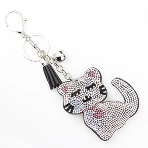 Détail d'un porte-clés chat avec strass blancs et roses et pompon en cuir noir élégant