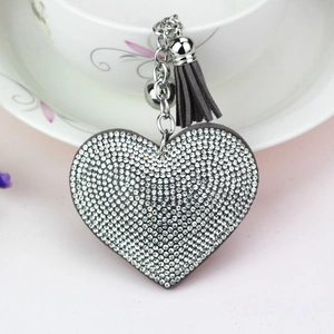 Detail of crystal heart keychain with grey leather tassel and silver bell accessory
