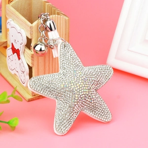 Detailed view of silver star keychain with iridescent crystals, bell and white leather tassel