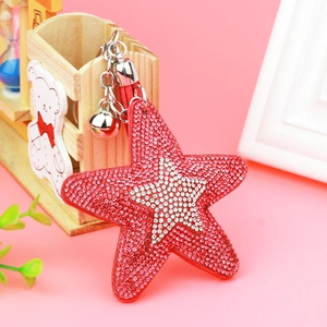 Detailed view of pentagram keychain with red and silver rhinestones on pink background