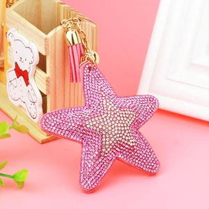 Detailed view of pink star rhinestone keychain with suede tassel and golden bell accent