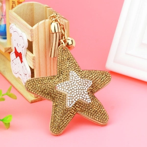 Detail of crystal star keychain with golden bell and beige tassel accessory