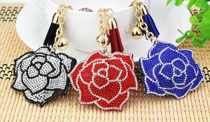 Detail of luxury rhinestone rose keychains with suede tassels in black, red, and blue colors