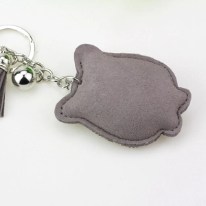 Detailed view of a grey velvet owl keychain with tassel, bell, and silver metal ring