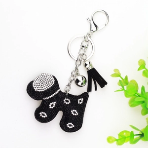 Detail of a black velvet dog keychain with white rhinestones, silver bell and tassel