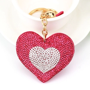 Dettaglio portachiavi a cuore con strass e nappa rosa su una tazza di ceramica