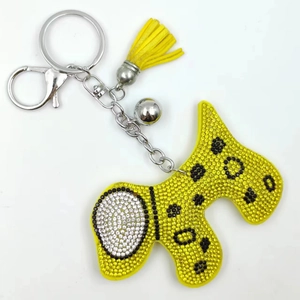 Détail d'un porte-clés chien jaune scintillant avec pompon en velours et clochette