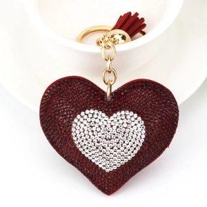 Dettaglio portachiavi a cuore rosso con strass e nappa su una tazza di ceramica
