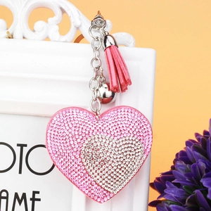 Dettaglio portachiavi a cuore con strass rosa, campanellino e nappa in pelle elegante